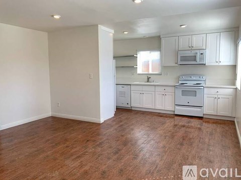 A kitchen with white cabinets and a wooden floor.