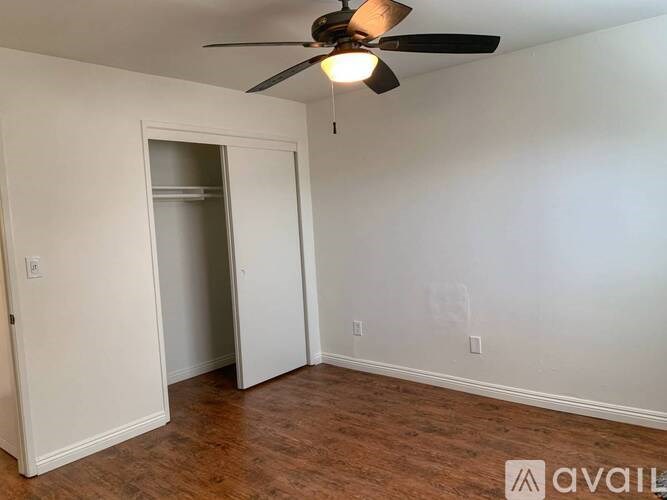 A room with a ceiling fan and a doorway leading to another room.
