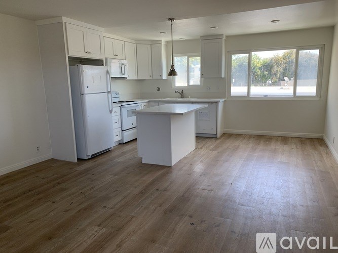 A kitchen with white appliances and wooden floors.