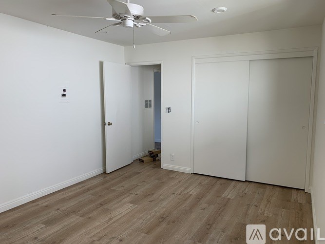 A room with a ceiling fan and wooden flooring.