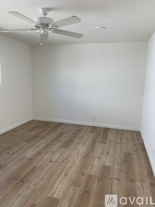 A room with a ceiling fan and wooden flooring.