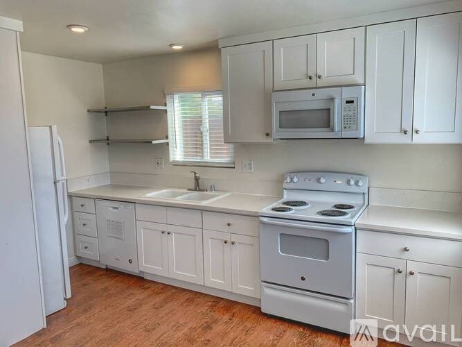 A kitchen with white cabinets and a stove top oven.