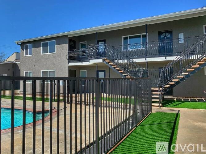 A multi-story apartment building with a pool and a black fence.