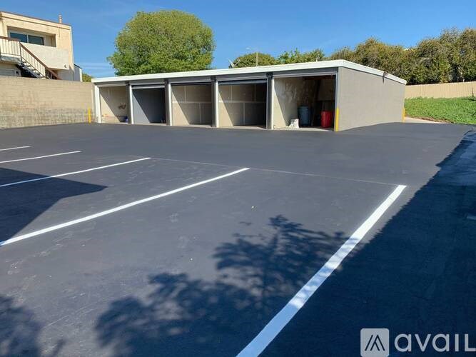 A parking lot with a building and a tree in the background.