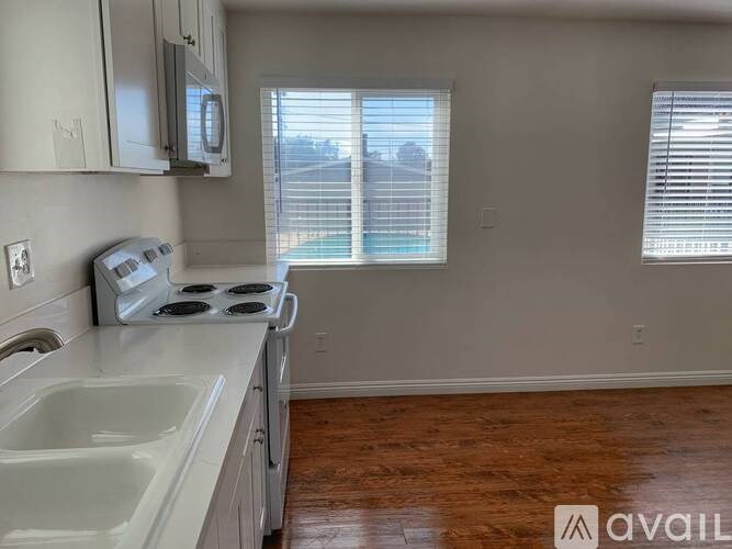 A kitchen with a stove, sink, and cabinets.
