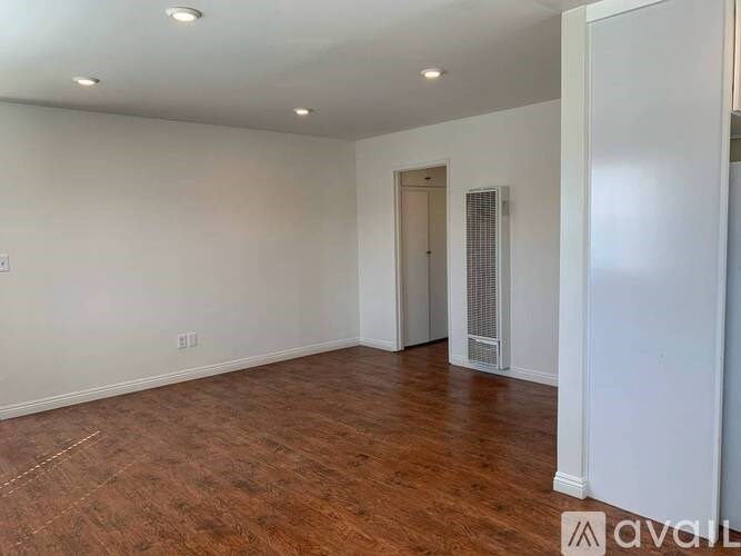 A room with wooden flooring and white walls.