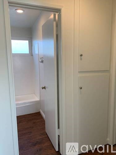 A white bathroom with a towel rack and a wooden floor.