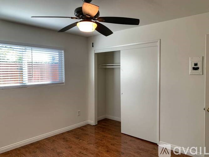 A room with a ceiling fan and a window with blinds.