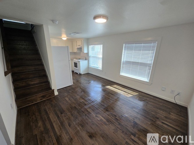 A room with wooden floors and a staircase leading to another level.