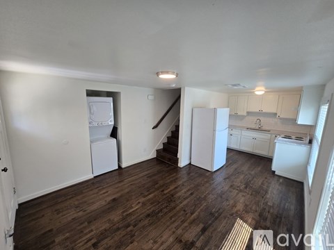 A kitchen with white appliances and wooden floors.
