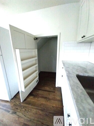 A white kitchen with a wooden floor and a white fridge.