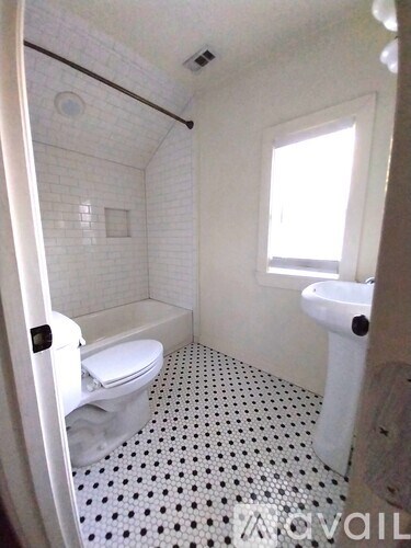 A white bathroom with a toilet, sink, and a shower.