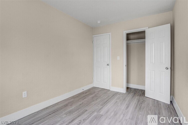 A room with two white doors and a wooden floor.