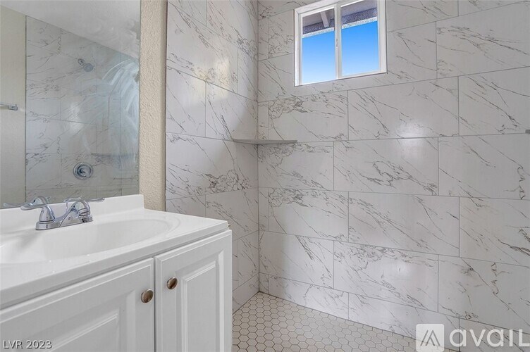 A bathroom with a marble wall and a window.