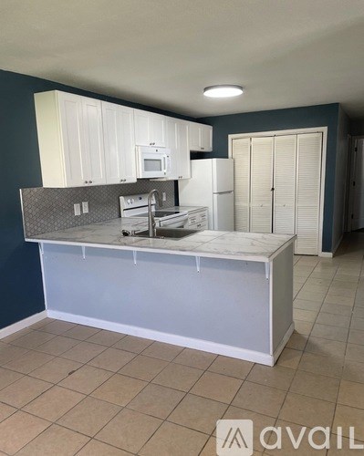 A kitchen with white appliances and cabinets.
