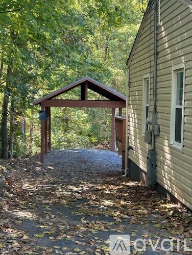A small wooden structure sits in the middle of a leaf-covered path.