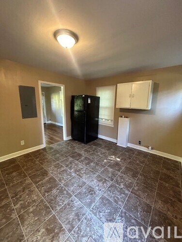 A kitchen area with tile flooring and a black refrigerator.