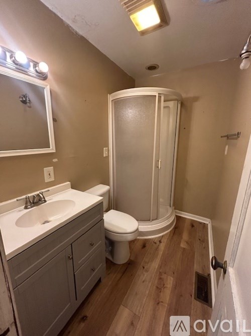 A bathroom with a toilet, sink, and shower stall.
