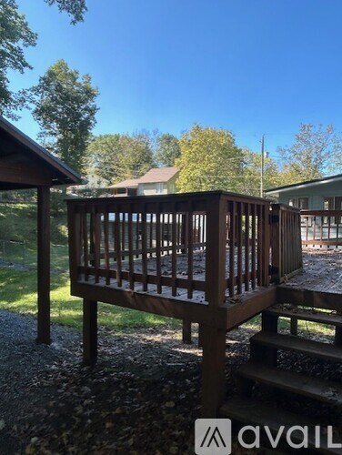 A wooden deck with a bench and a house in the background.