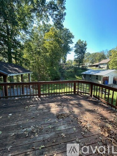 A wooden deck with leaves on it and a house in the background.