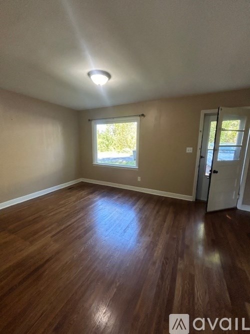 A room with wooden flooring and a window letting in natural light.