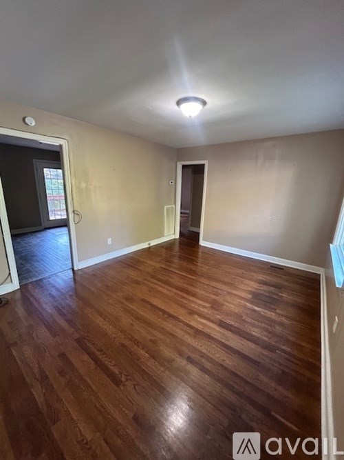 A room with wooden flooring and a door in the middle.