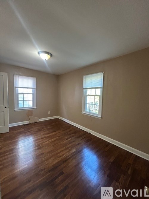 A room with wooden floors and two windows.