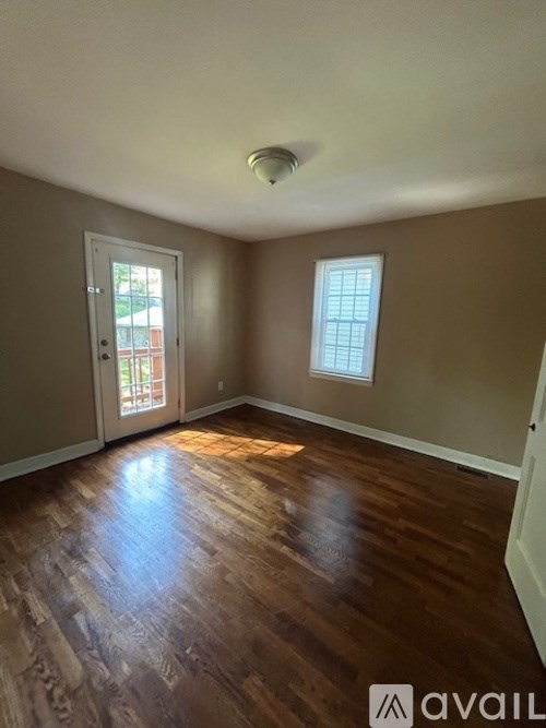A room with brown wooden floors and a window.