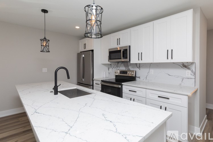 A kitchen with a marble countertop and white cabinets.