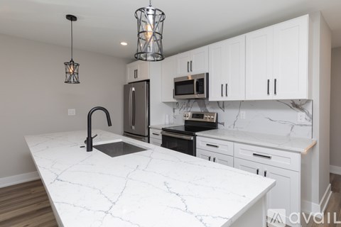 A kitchen with a marble countertop and white cabinets.