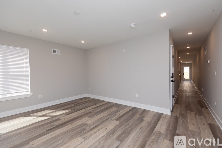 A spacious room with wooden flooring and a long hallway.