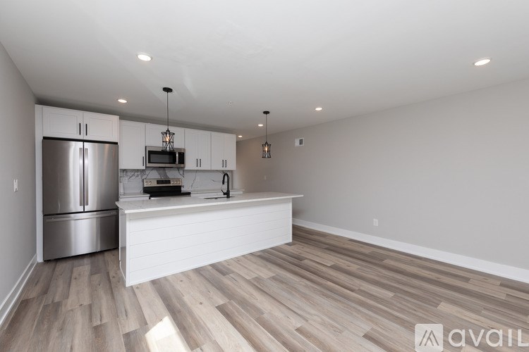 A kitchen with a refrigerator, microwave, and a countertop with a hanging light fixture.