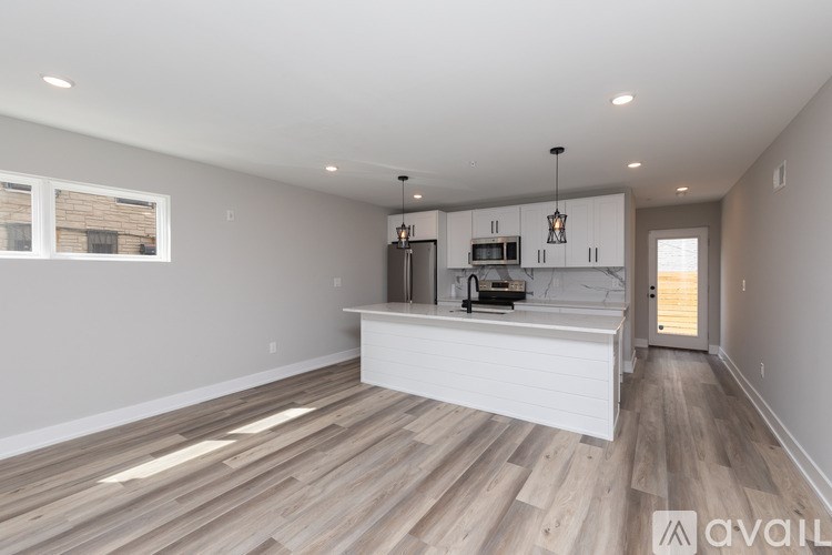 A spacious room with wooden flooring and a kitchen island in the middle.