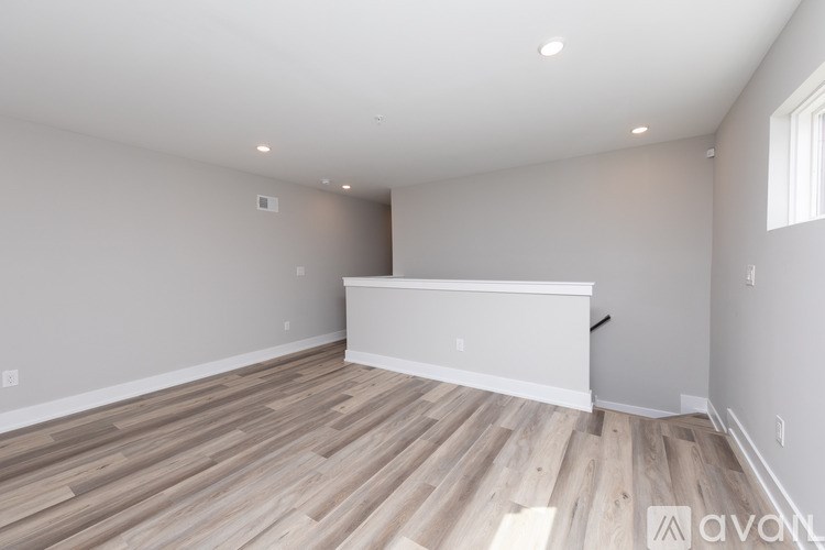 A spacious room with wooden flooring and white walls.