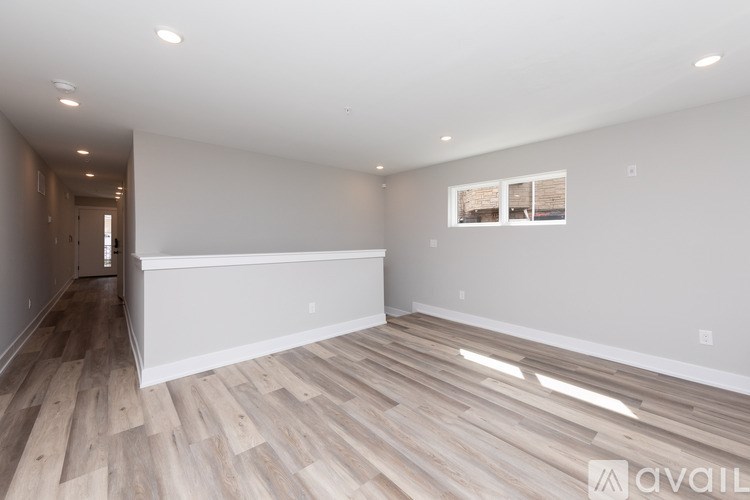 A spacious room with wooden flooring and white walls.