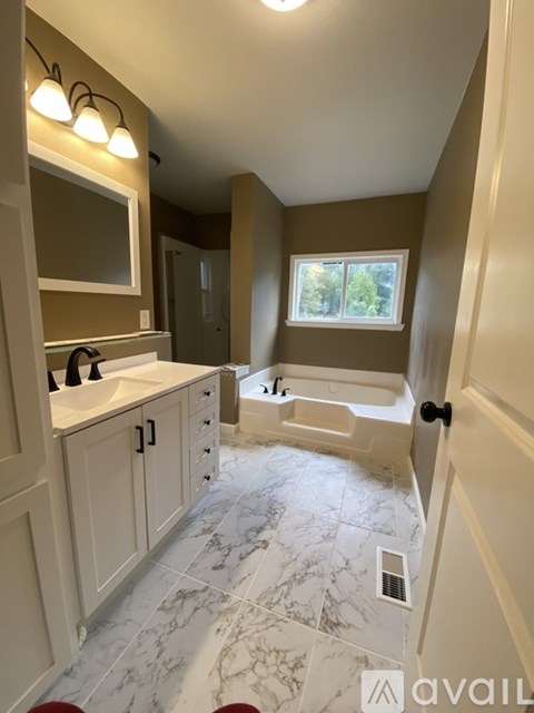 A bathroom with a marble floor and a window showing trees outside.