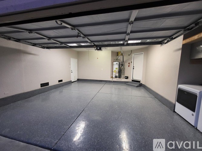 A spacious garage with a grey floor and a white cabinet on the right side.