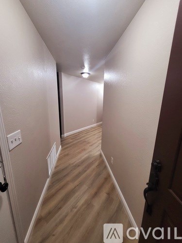 A hallway with wooden floors and white walls.