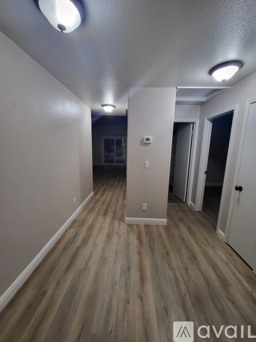 A hallway with wood flooring and white walls.