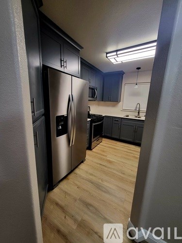 A kitchen with a stainless steel refrigerator and wooden flooring.