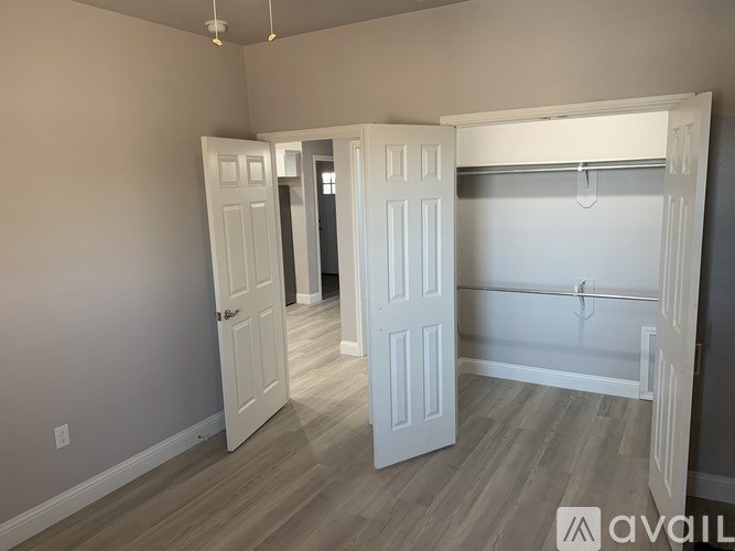 A room with two white doors and a bed in the other room.