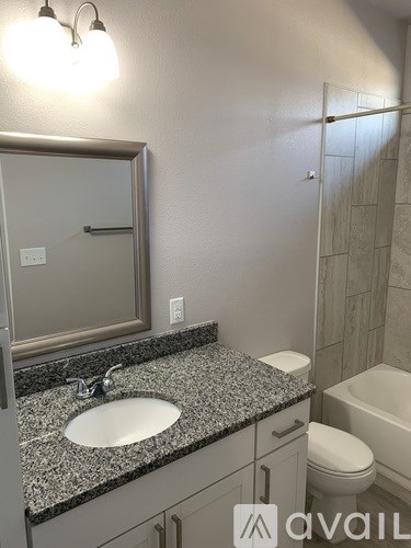A bathroom with granite countertops and a white toilet.