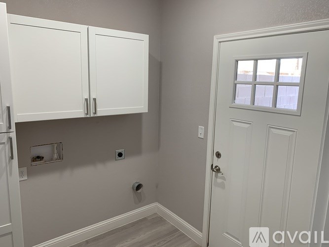 A white door with a window above it in a room with white cabinets.