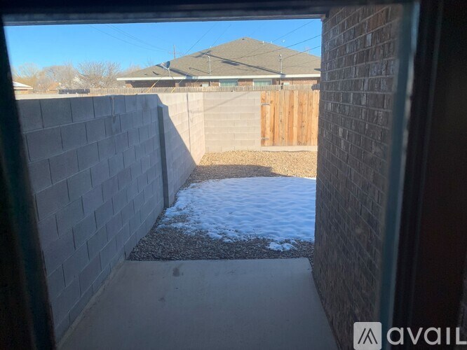 A backyard with a wooden fence and a small patch of snow on the ground.