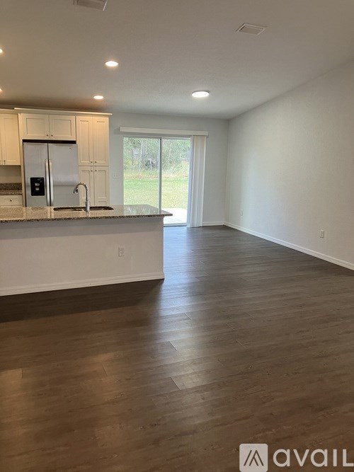 A kitchen with white cabinets and a white fridge with a sink underneath it.
