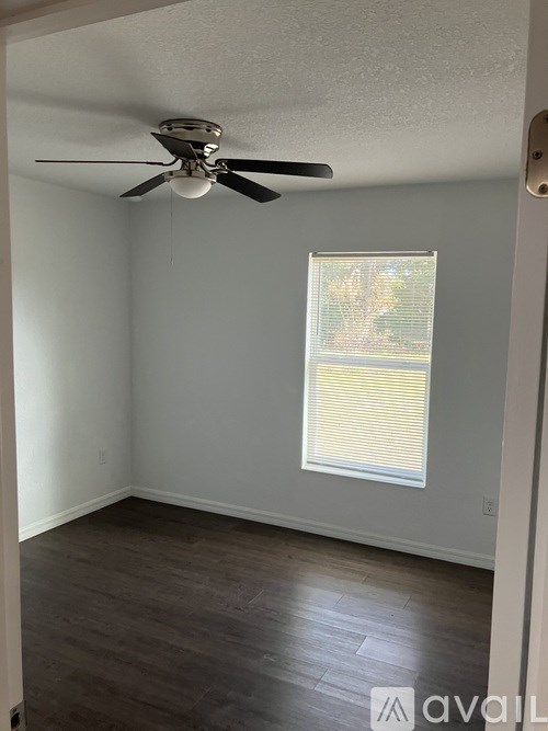 A room with a ceiling fan and a window with blinds.