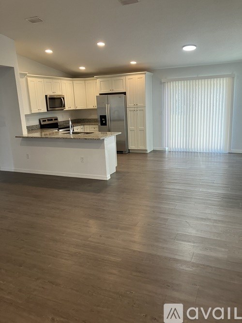 A kitchen with white cabinets and a wooden floor.