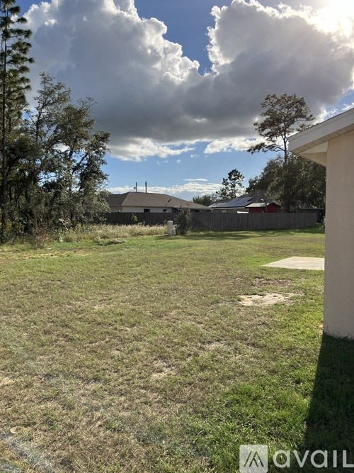 A grassy field with a cloudy sky and a house in the distance.