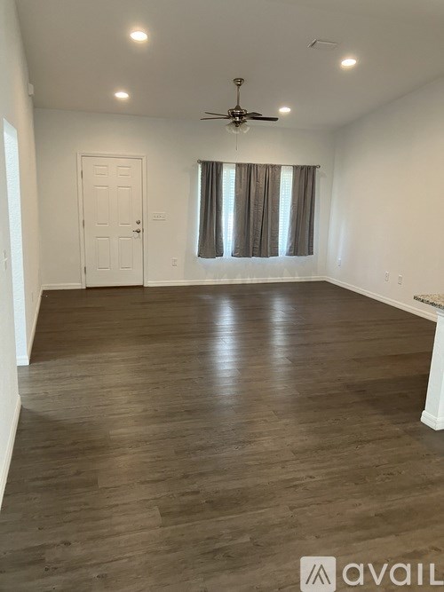 A spacious room with wooden flooring and a ceiling fan.