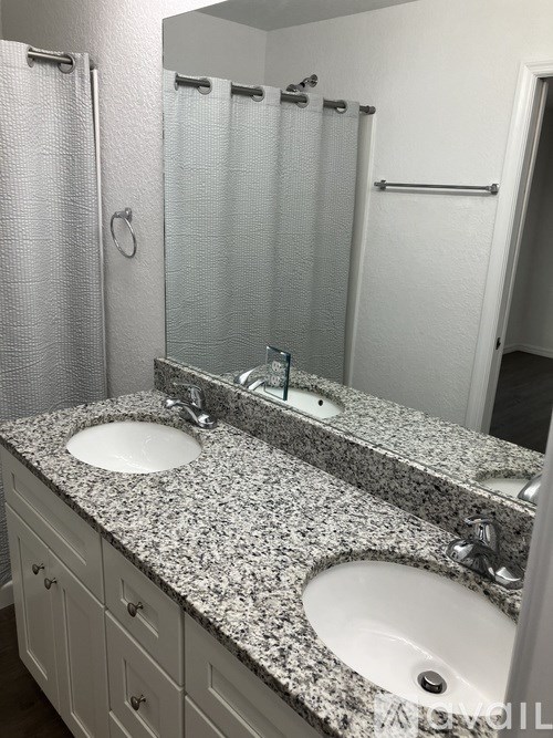 A bathroom with two sinks and a shower.